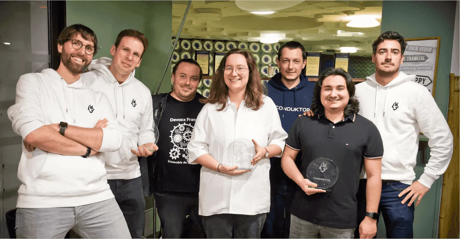 Group photo of seven Conduktor team members posing with two glass company awards